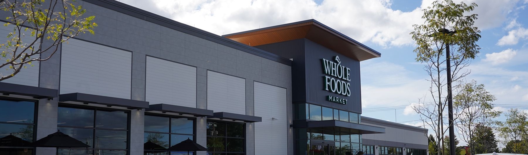Whole Foods Market exterior with wall panels, a wood-tone canopy and storefront glazing