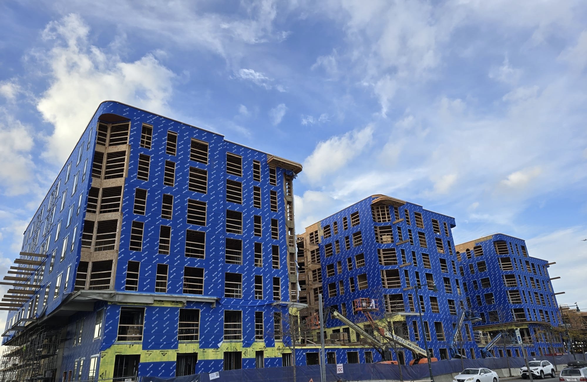 Multifamily buildings under construction fully wrapped in blue air and water barrier