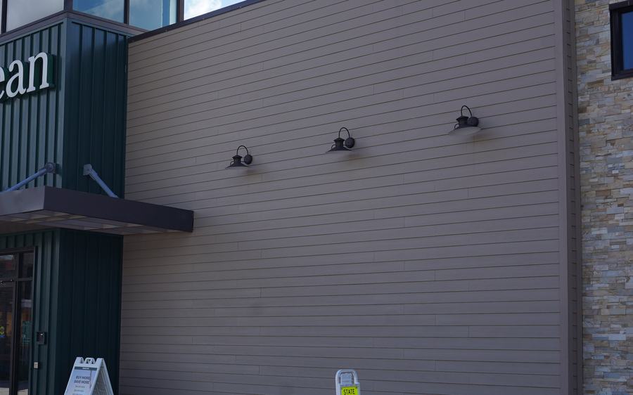 Horizontal siding wall beside a storefront entrance and stone veneer corner